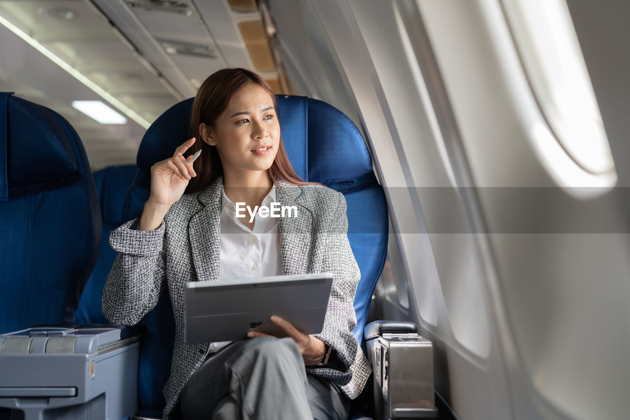 Businesswoman with digital tablet sitting in aeroplane