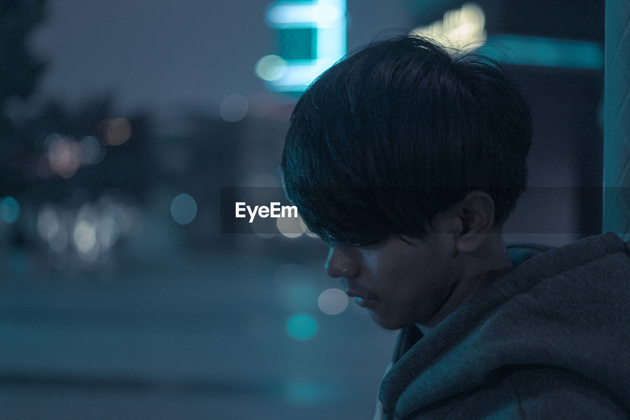 Close-up portrait of boy looking away at night