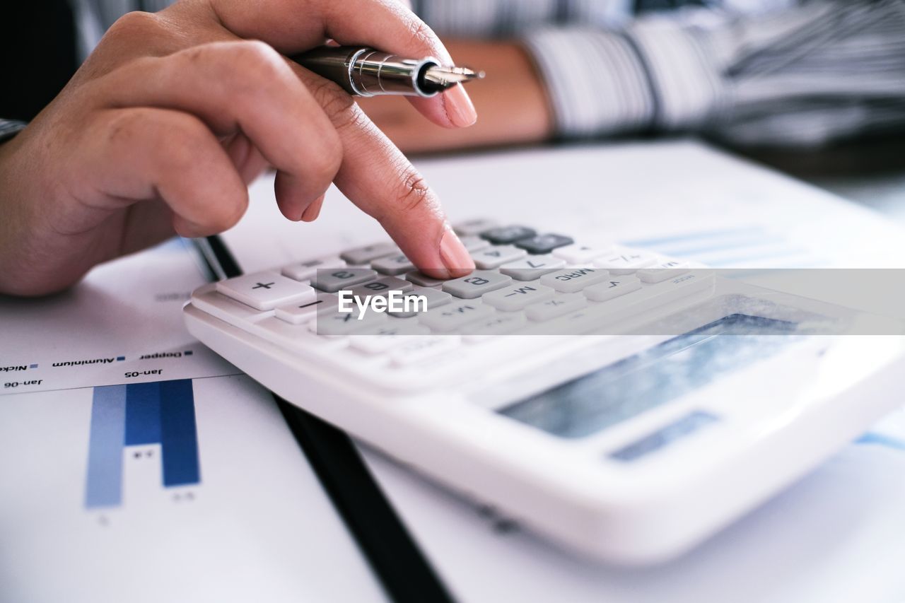 Cropped image of businesswoman using calculator in office