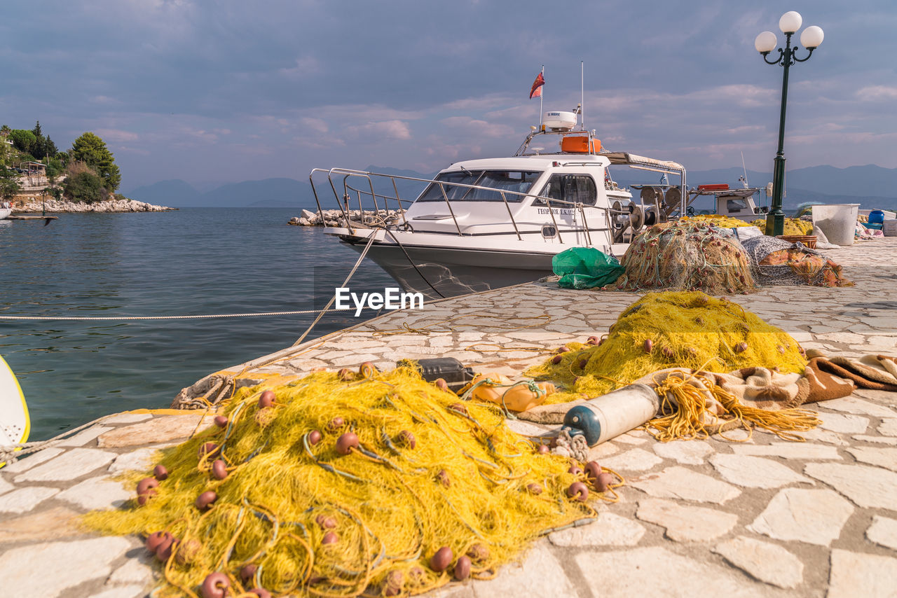 VIEW OF FISHING BOATS MOORED AT HARBOR AGAINST SKY