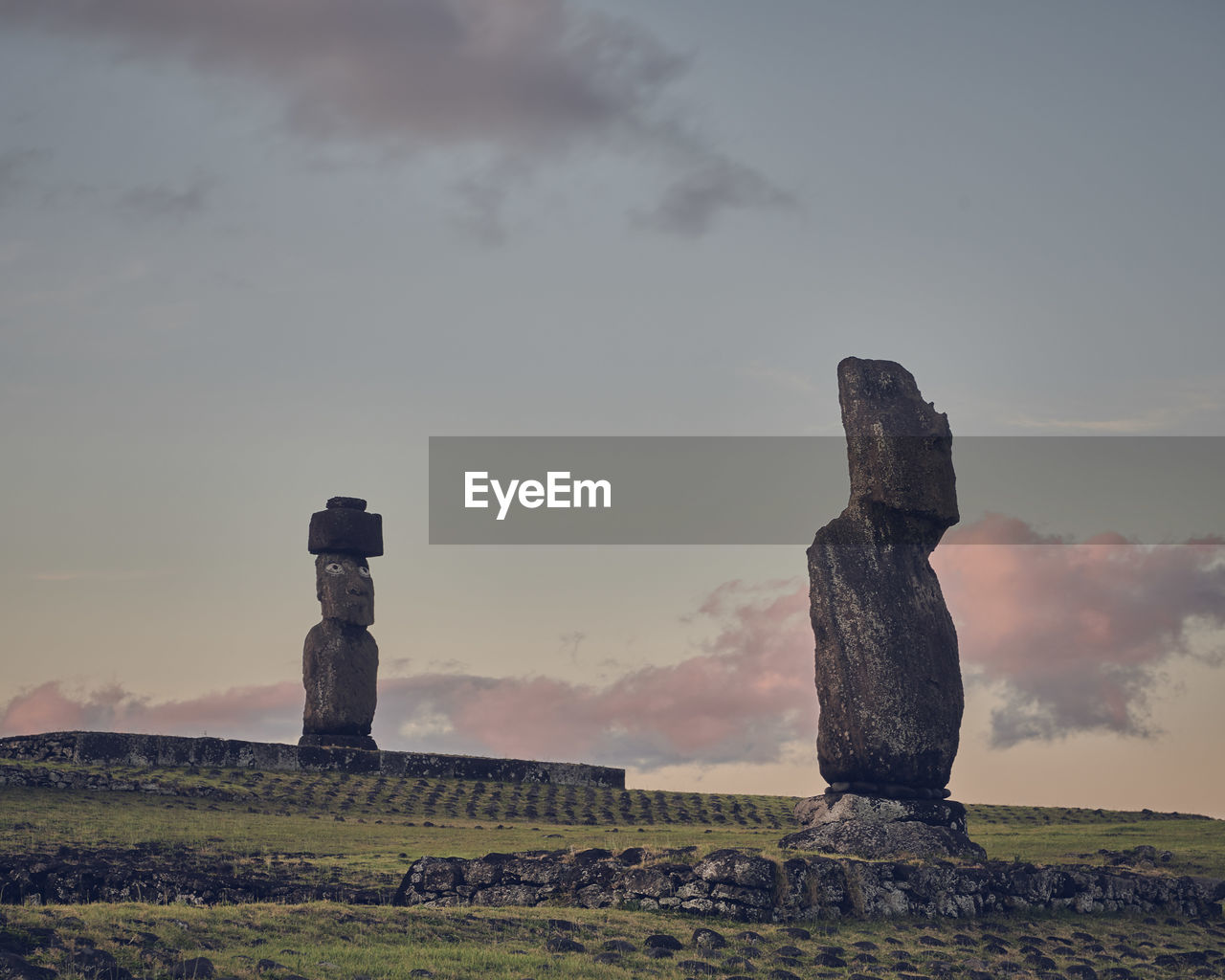 Moai statues on field against sky during sunset on rapa nui