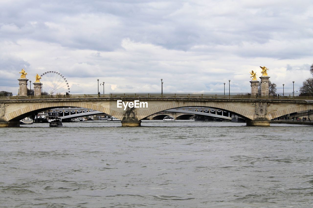 ARCH BRIDGE OVER RIVER IN CITY AGAINST SKY