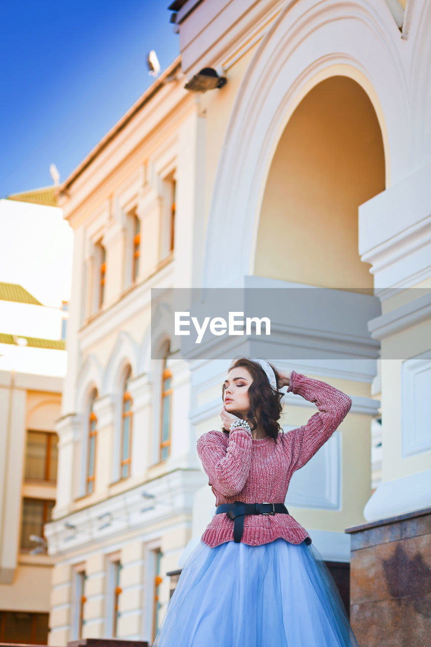 Young woman posing in front of building