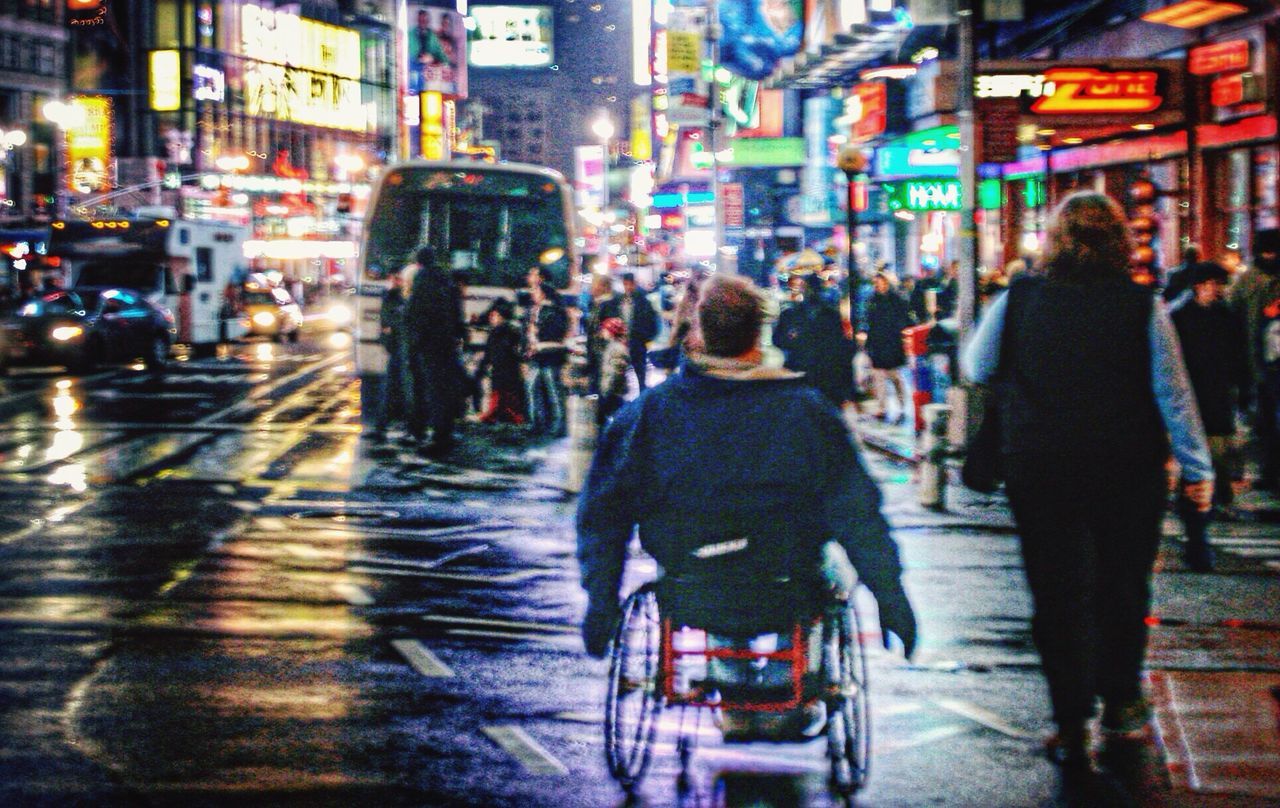 PEOPLE WALKING ON CITY STREET AT NIGHT