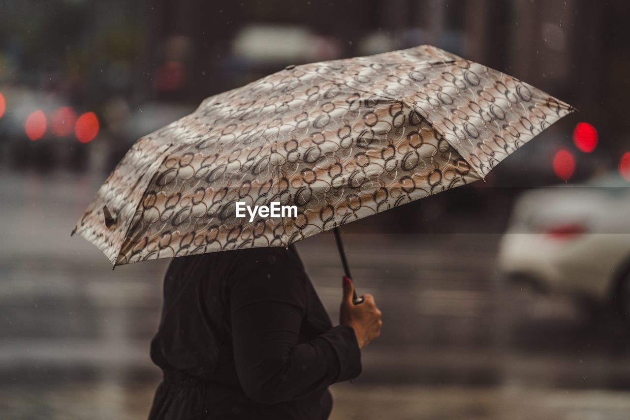 Woman with umbrella walking on wet street