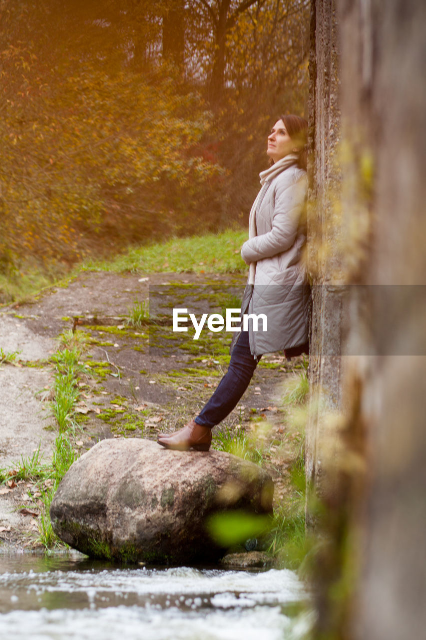 Side view of woman on rock in forest