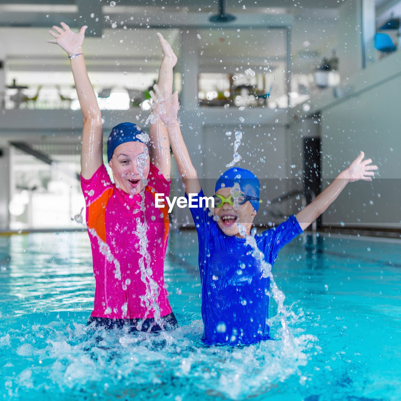 Cheerful young woman splashing water in swimming pool