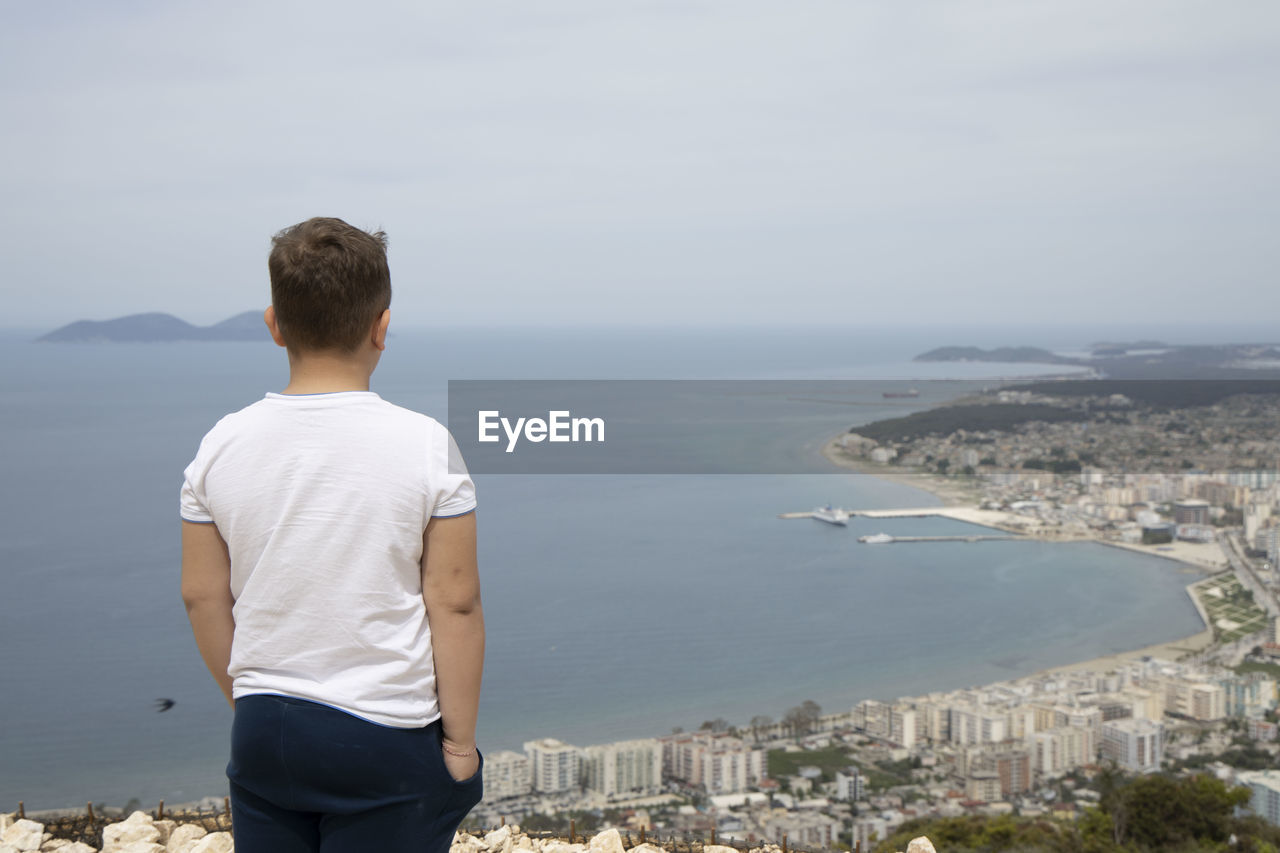 REAR VIEW OF MAN LOOKING AT CITYSCAPE