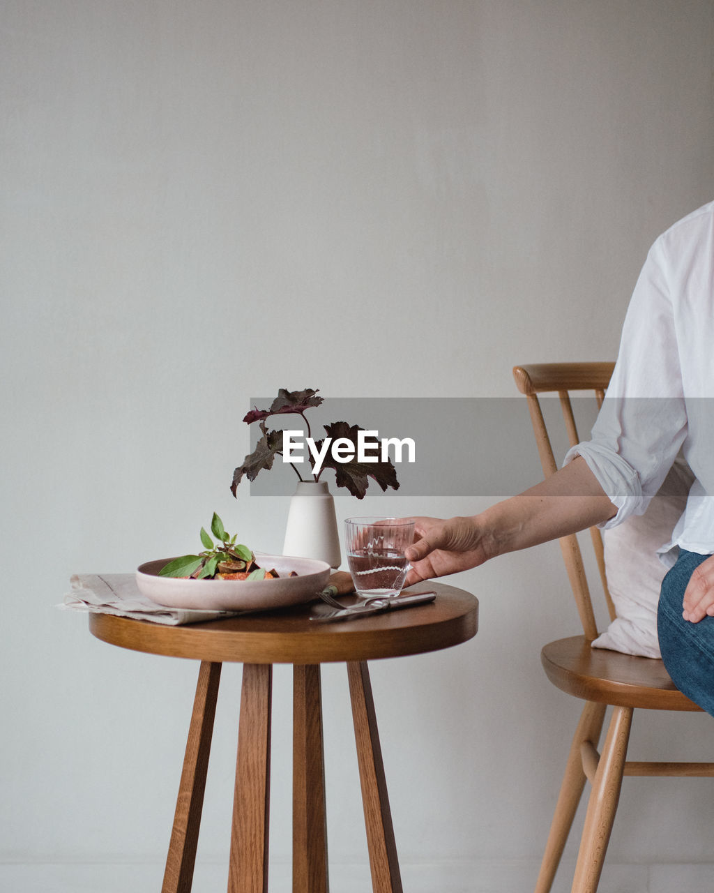 Woman holding drinking glass on wooden table at home