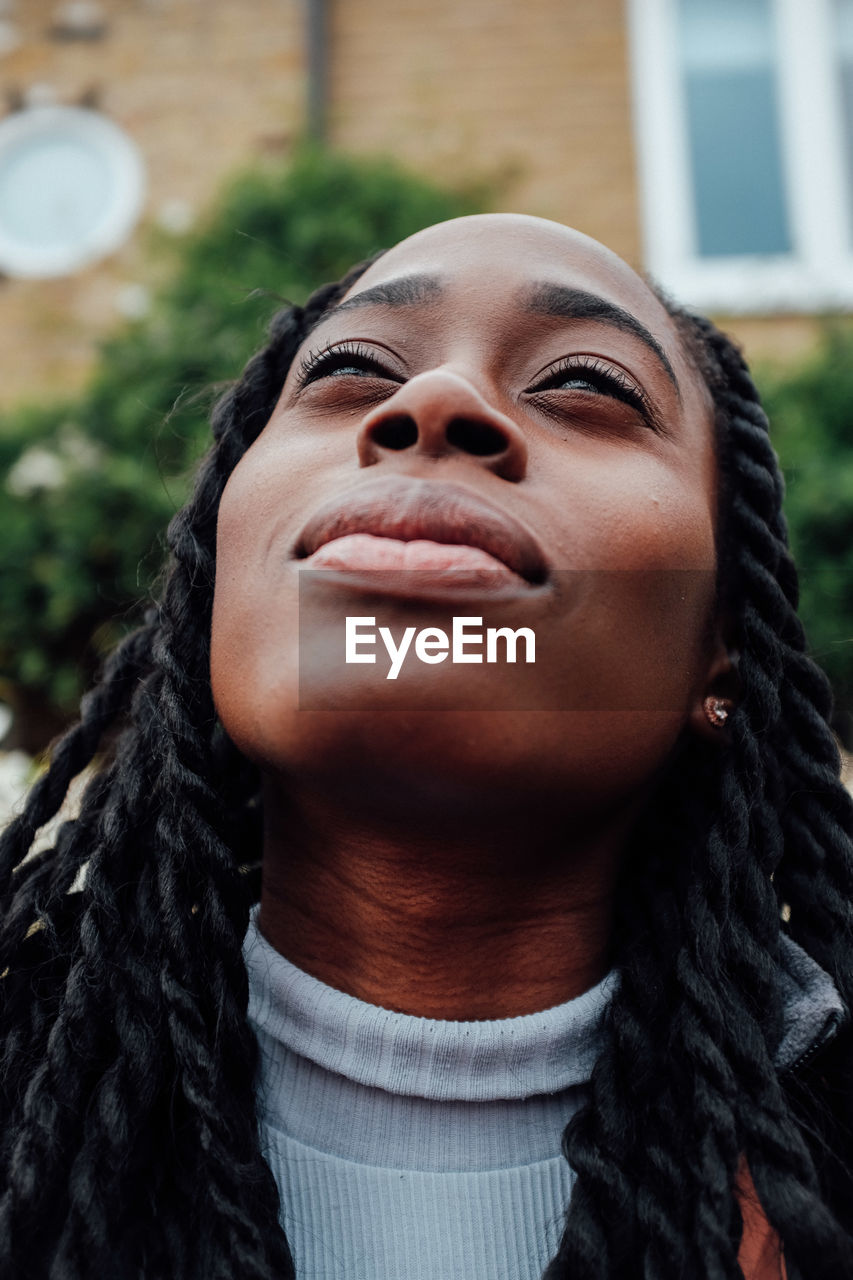 Close-up of young woman looking up in city