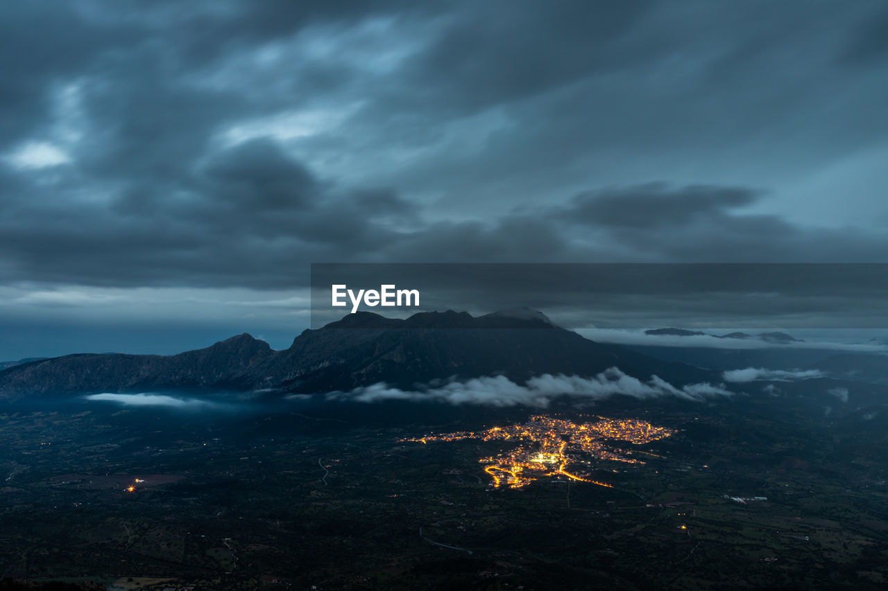 Scenic view of illuminated city of oliena against the mount corrasi at dusk