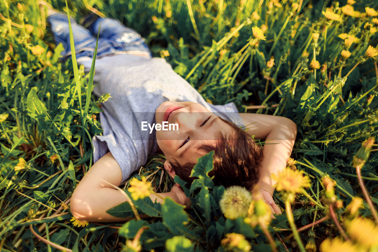 Cute little boy lying down on field and wide smiling