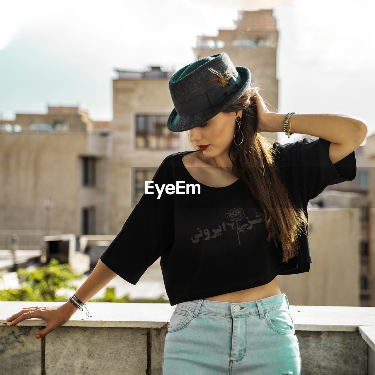 Side view of woman wearing hat while standing against wall