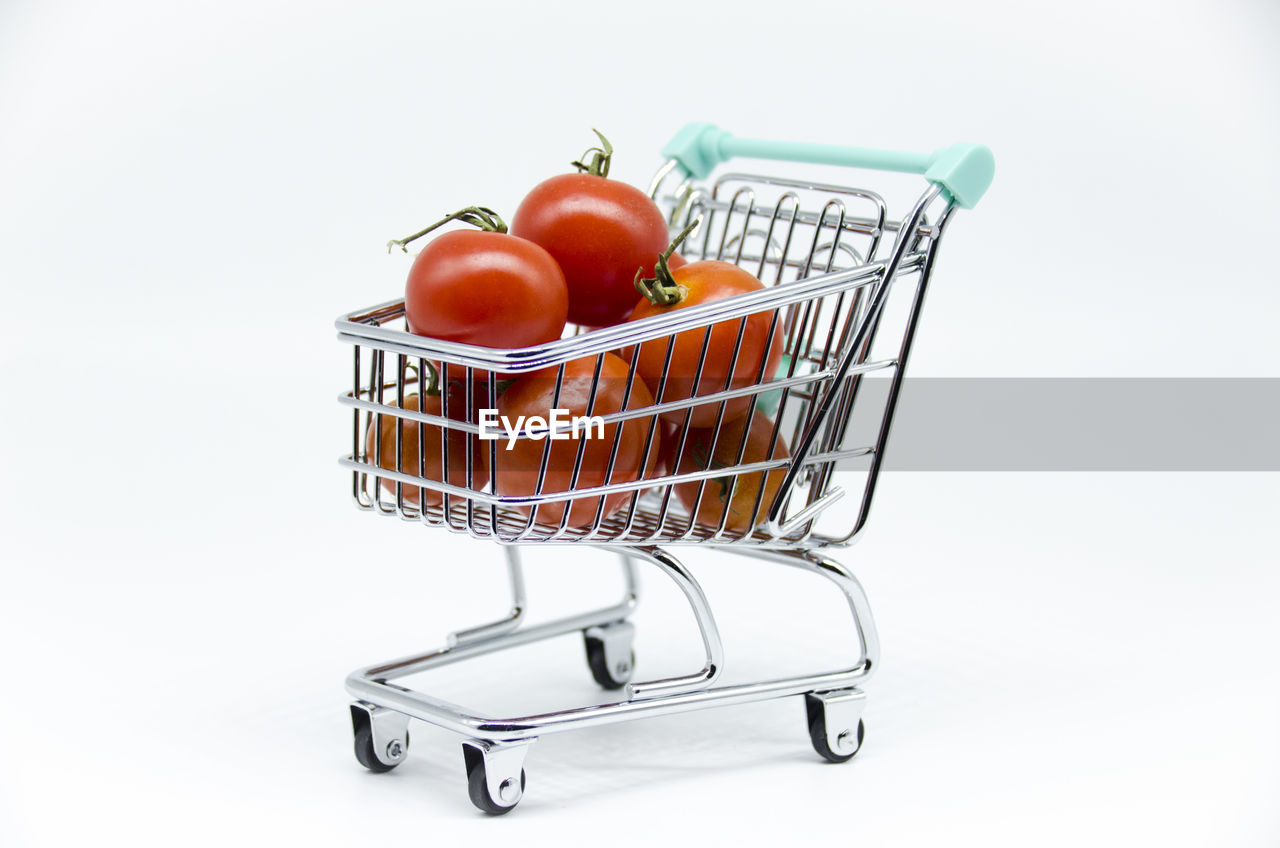 Close-up of tomatoes with basket on white background