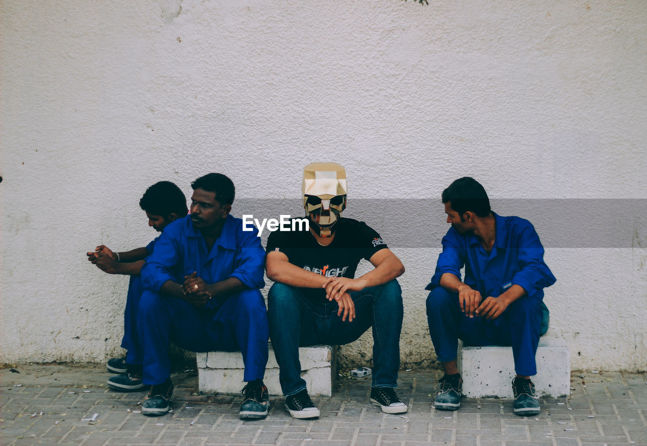 YOUNG MEN SITTING OUTDOORS