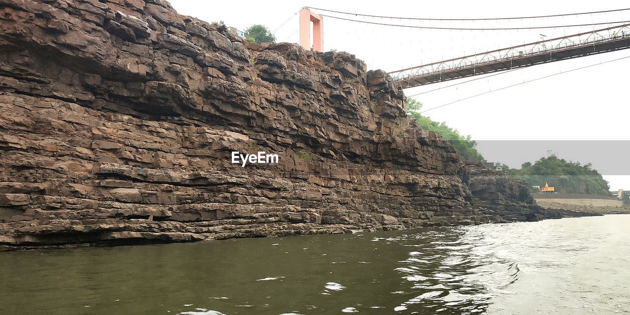 ROCK FORMATION BY RIVER AGAINST CLEAR SKY