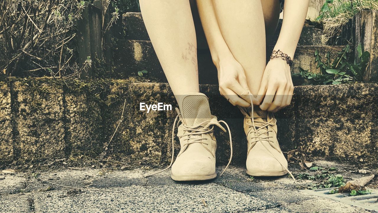 Low section of woman tying shoelace on steps