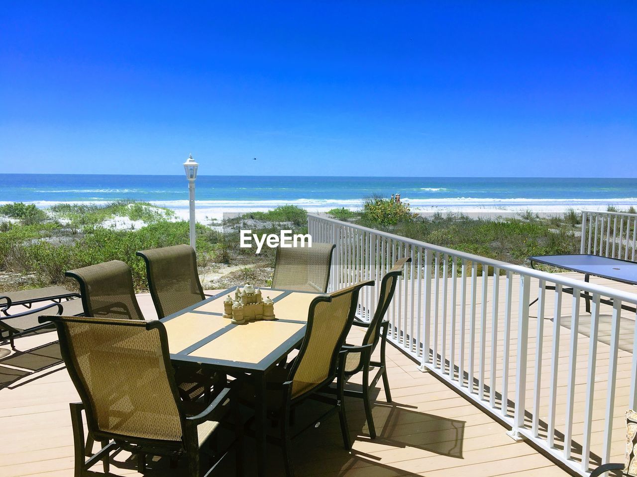 CHAIRS AND TABLES ON BEACH AGAINST CLEAR SKY