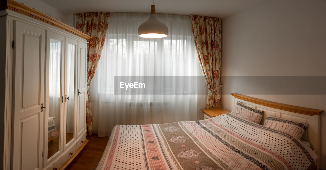 Interior of white cosy bedroom with curtains and sheets