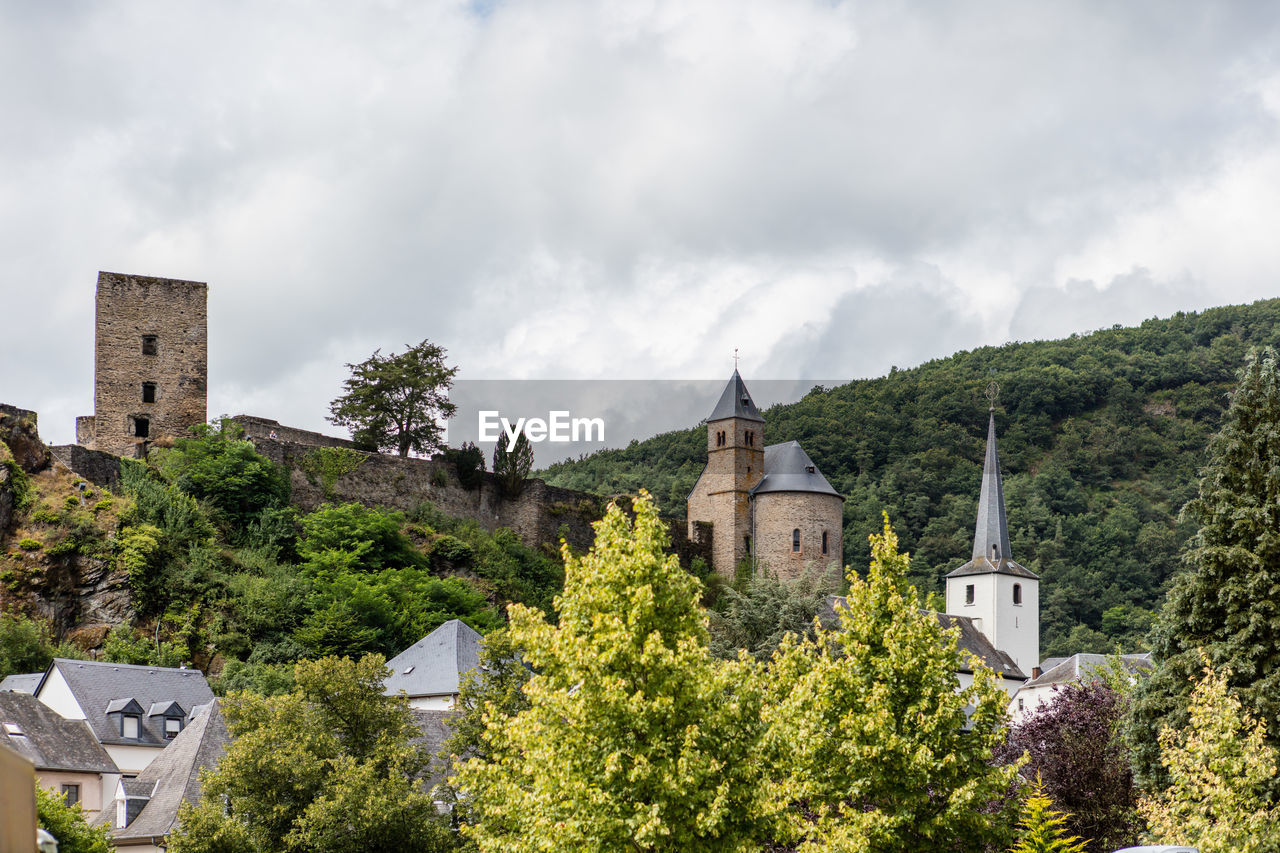 Low angle view of church and trees against cloudy sky