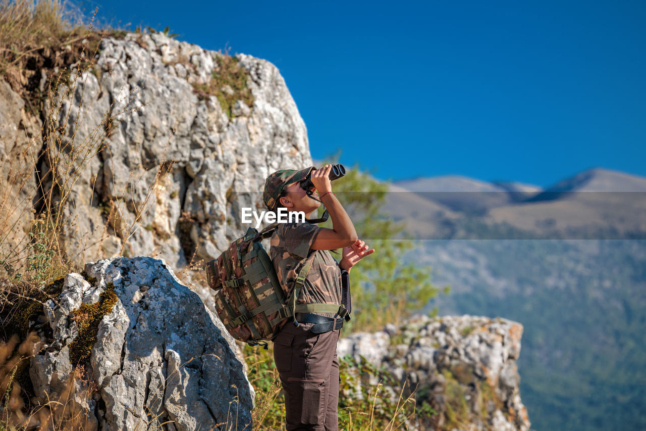 Observation of wild animals in nature. woman with binoculars in the mountains.