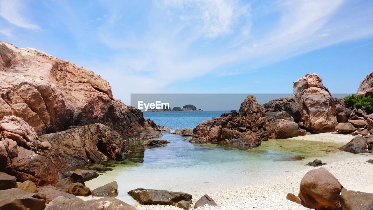 Rock formation on beach against sky