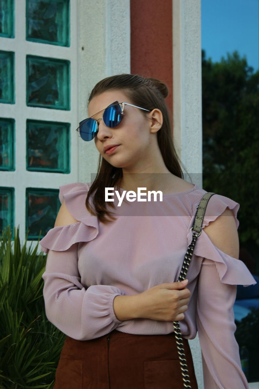 Young woman wearing sunglasses standing in city