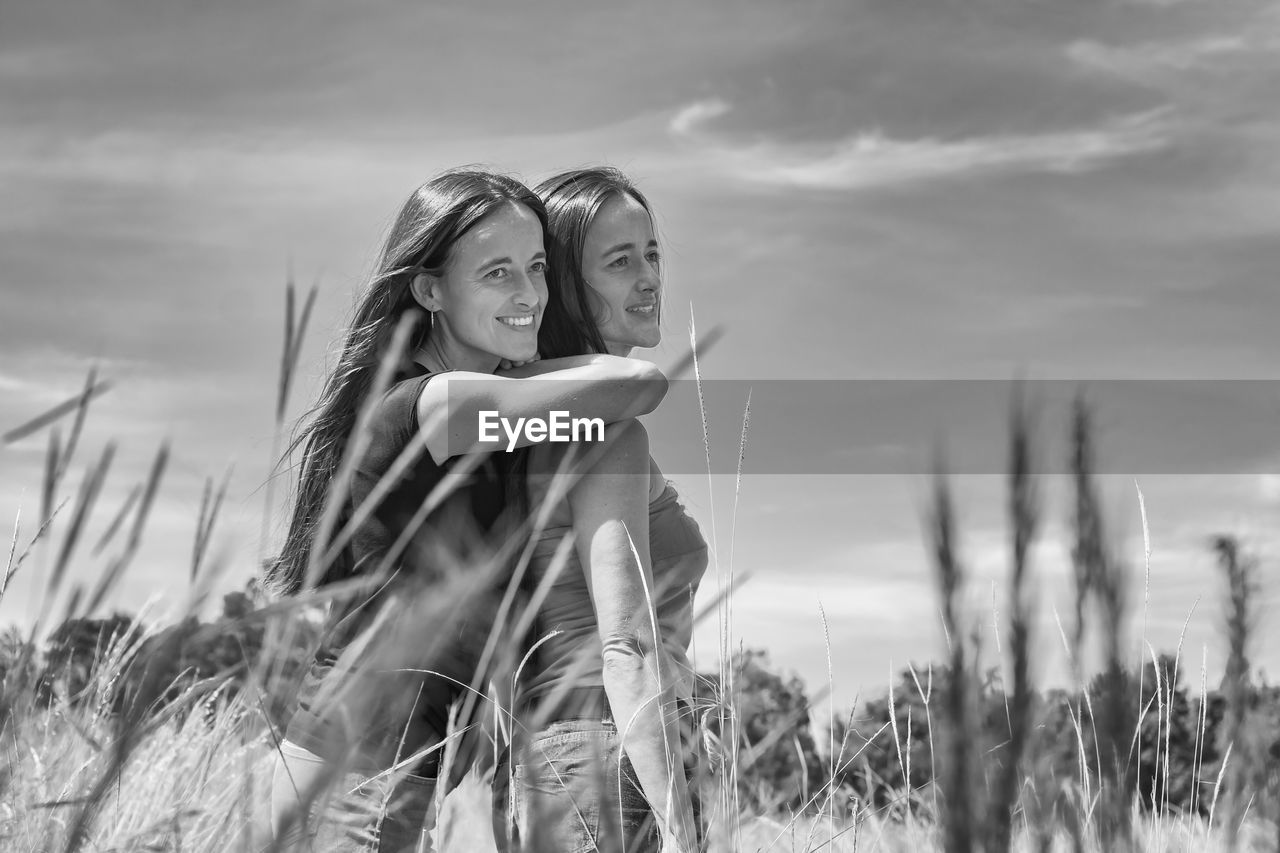 Women standing on field against sky