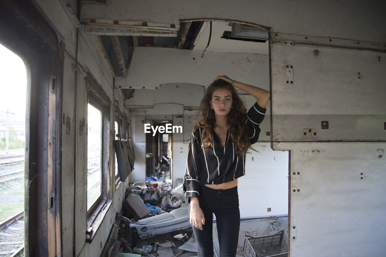 Portrait of young woman standing in abandoned train