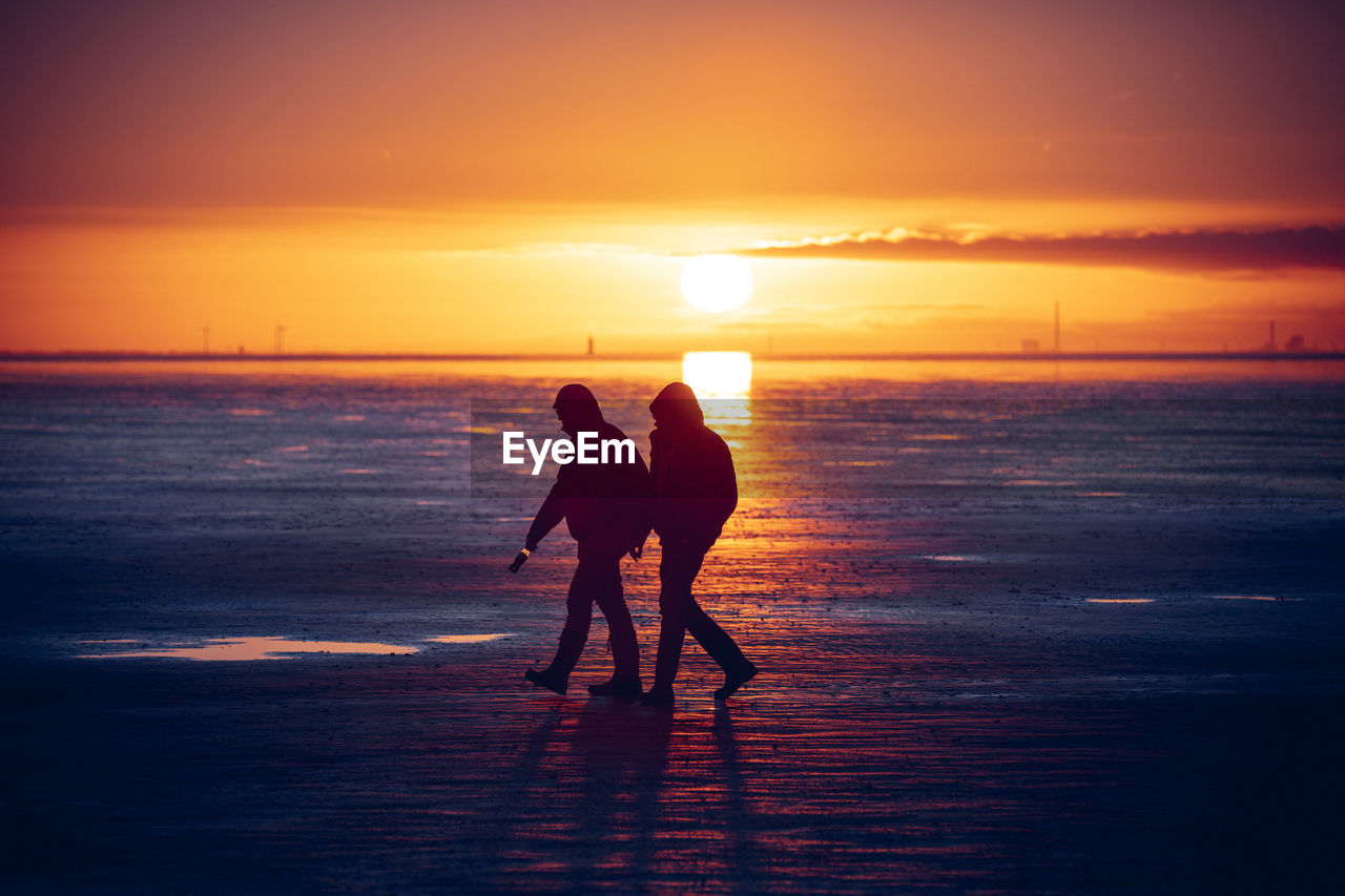 SILHOUETTE WOMEN ON BEACH DURING SUNSET