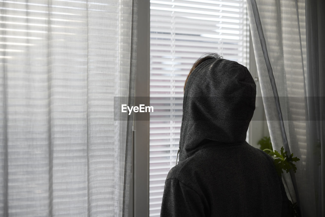 Rear view of person looking through window