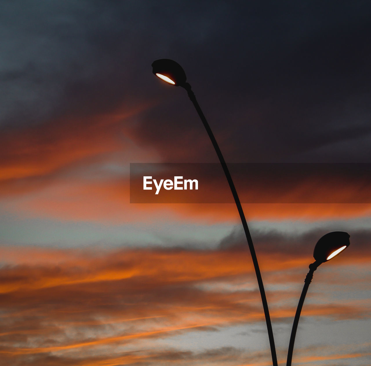 Low angle view of street light against dramatic sky