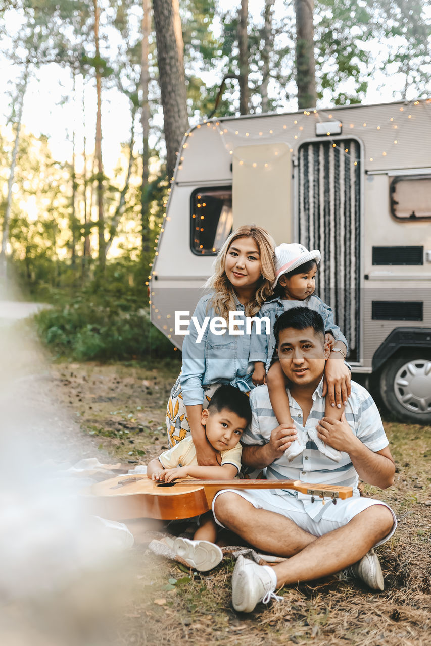 An asian family is vacationing traveling on a road trip by a camper car in the forest in nature