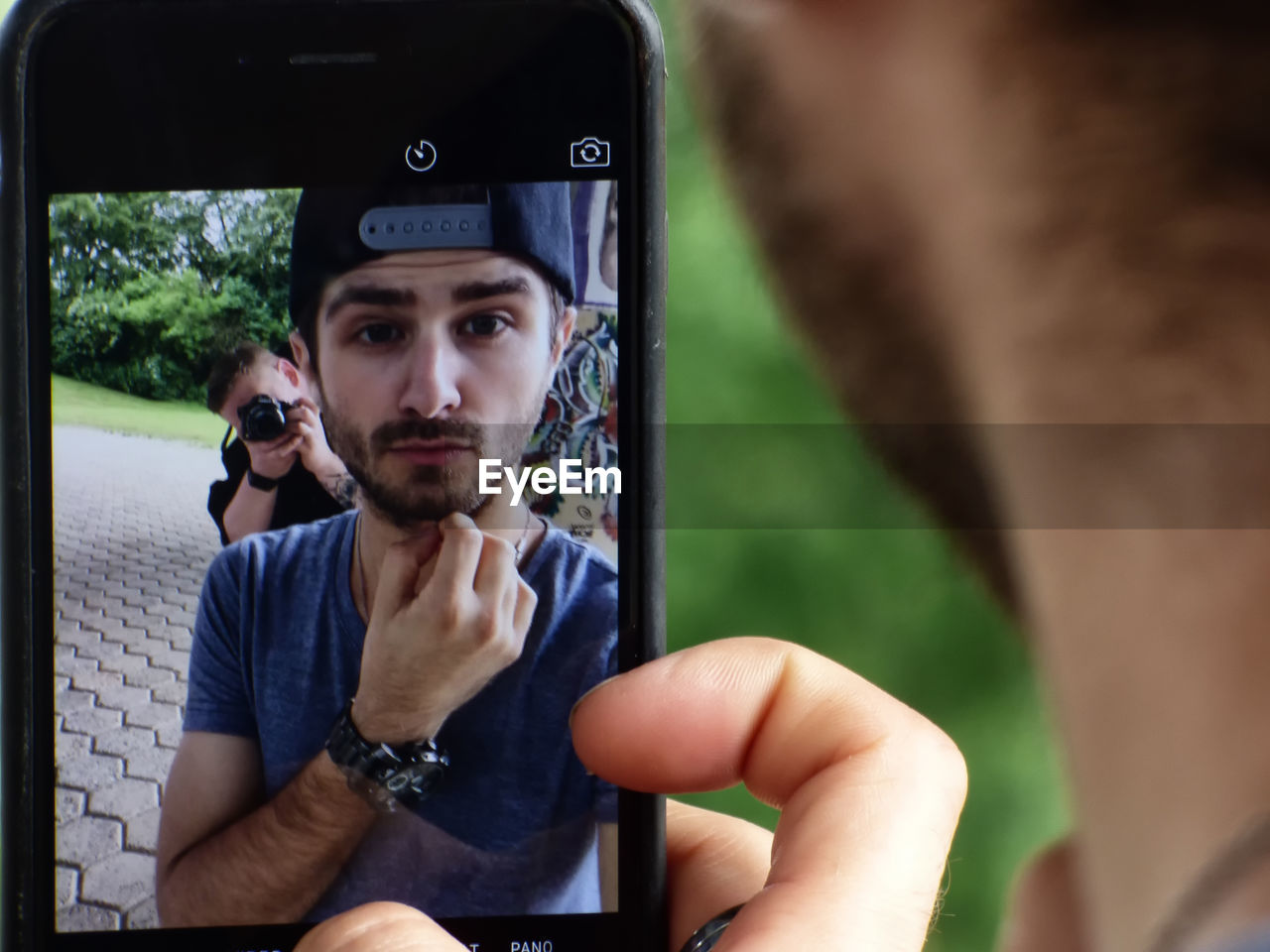 Young man taking selfie while friend photographing in background