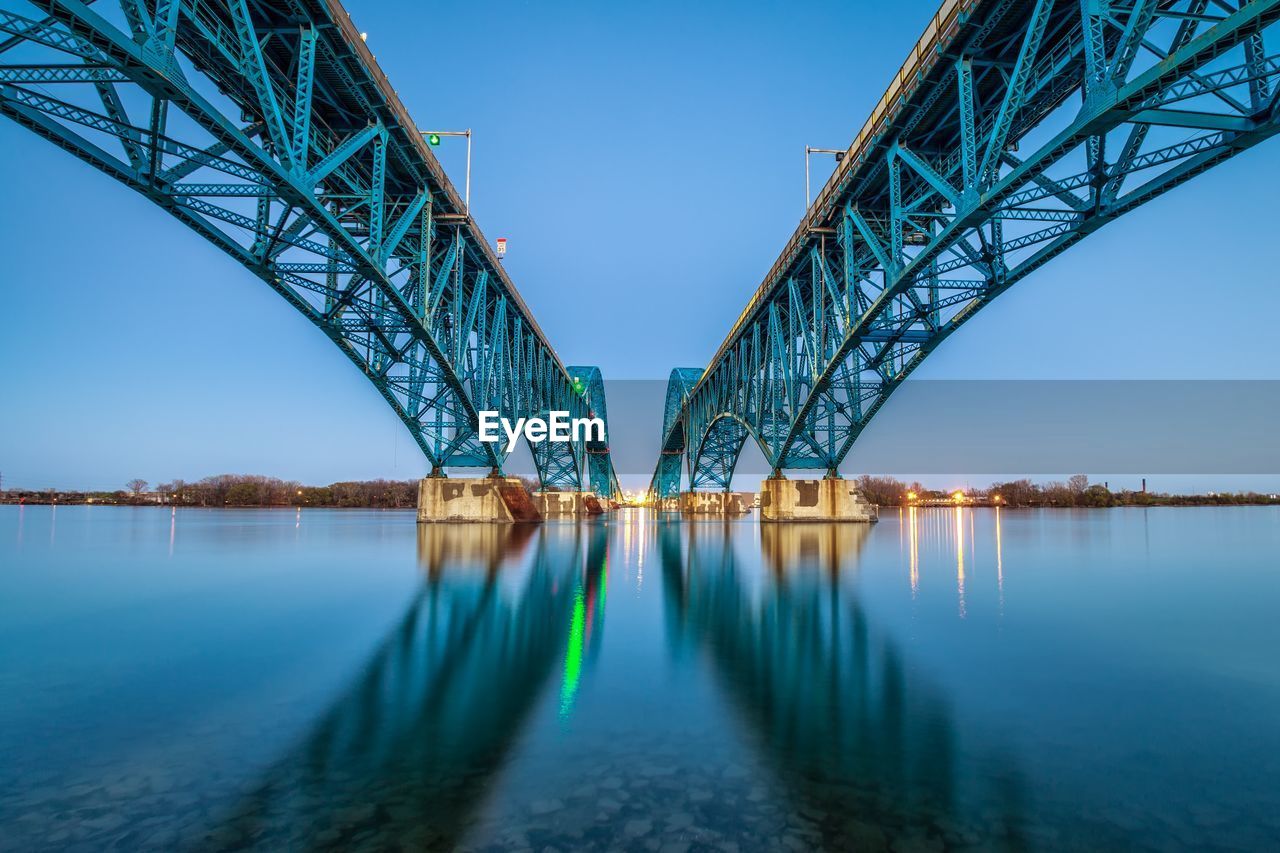 Low angle view of bridge over river against clear sky during sunset
