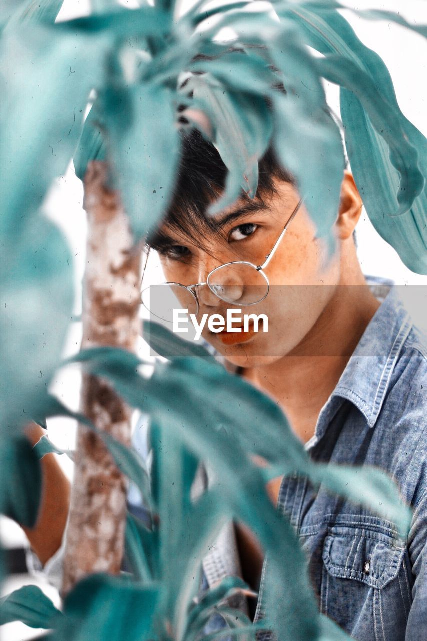 Portrait of young man with plants in foreground