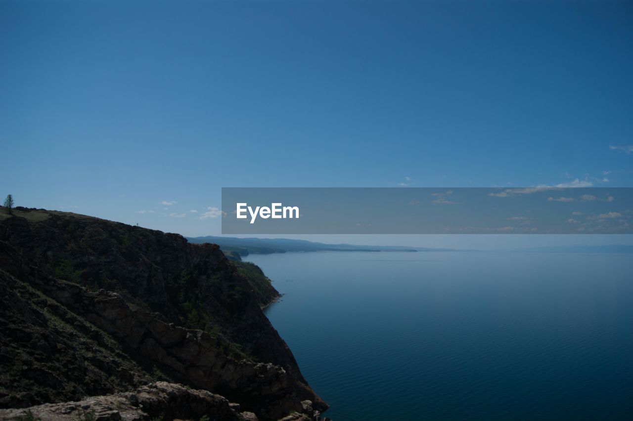 Scenic view of sea and mountains against blue sky