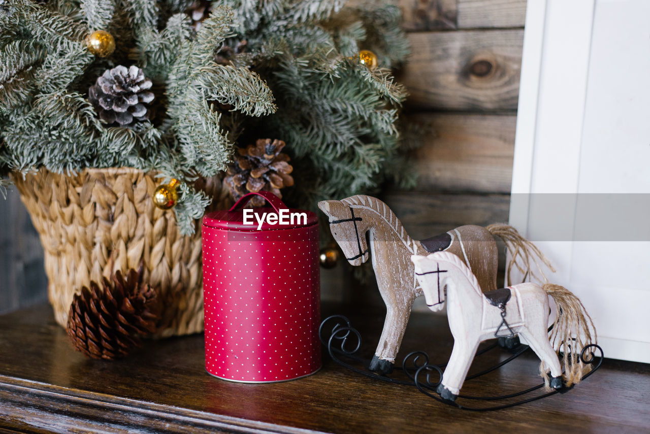 A souvenir horse, a raspberry tin can against a background of fir branches in a wicker basket