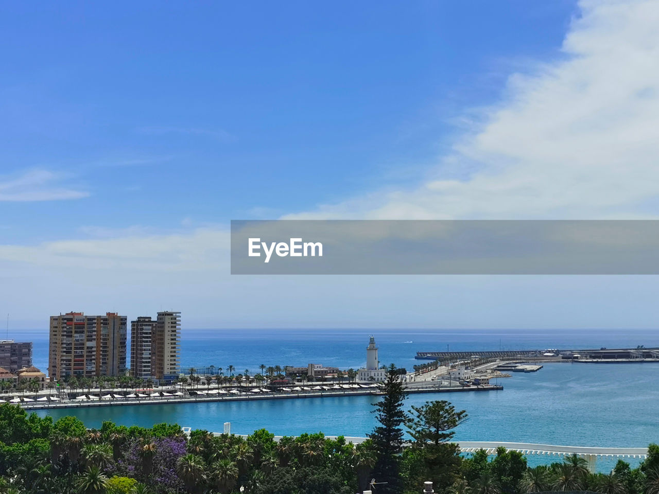 SCENIC VIEW OF SEA BY BUILDINGS AGAINST BLUE SKY