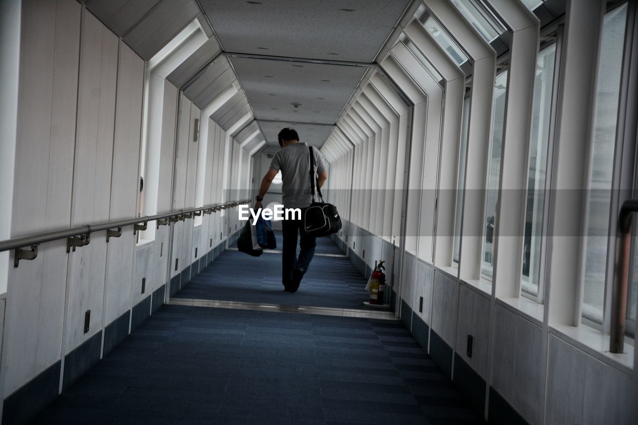 Rear view of man walking in corridor. end of the trip.