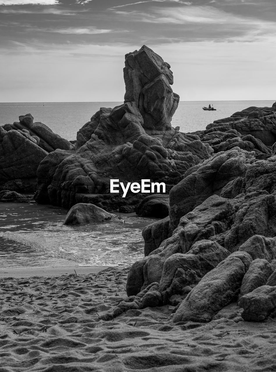 Rock formation at beach against sky