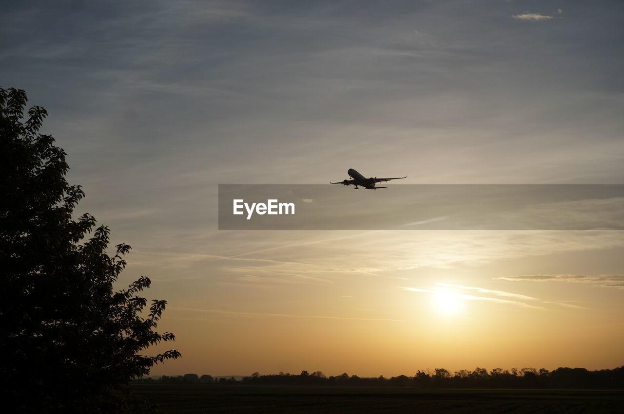 LOW ANGLE VIEW OF SILHOUETTE AIRPLANE AGAINST SKY DURING SUNSET