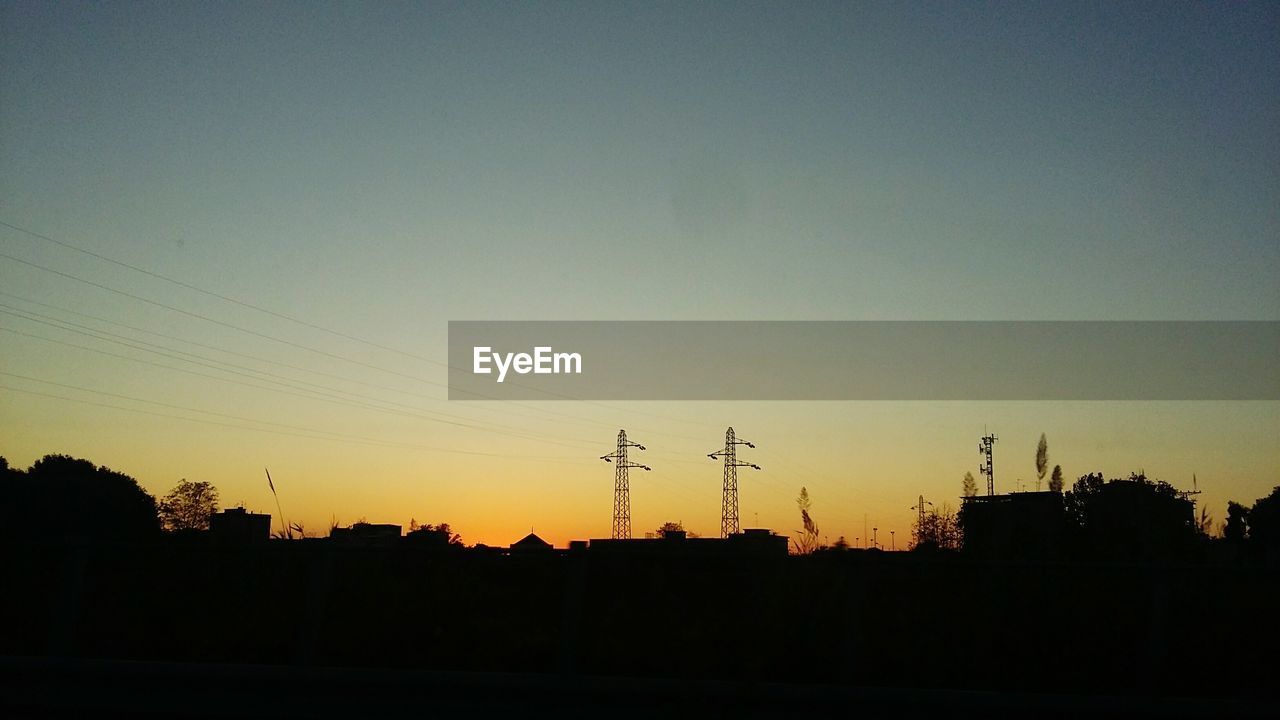 SILHOUETTE OF ELECTRICITY PYLONS AGAINST CLEAR SKY