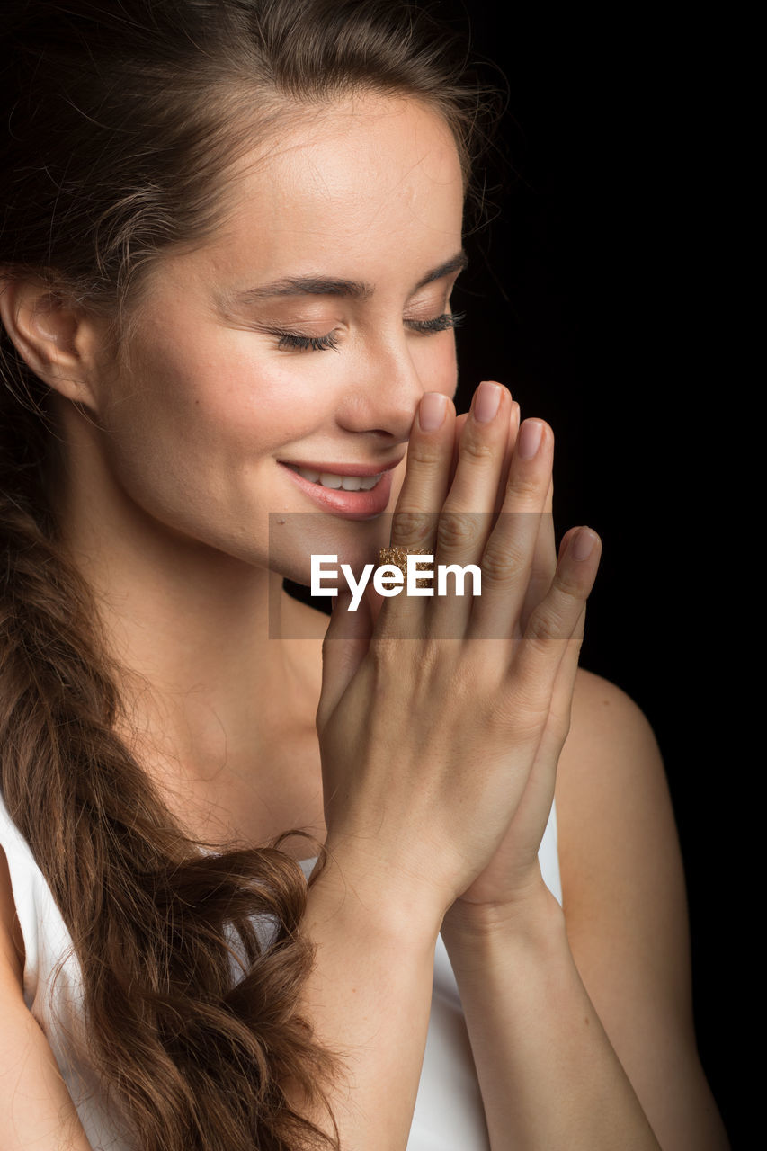 Close-up of smiling woman with hands clasped