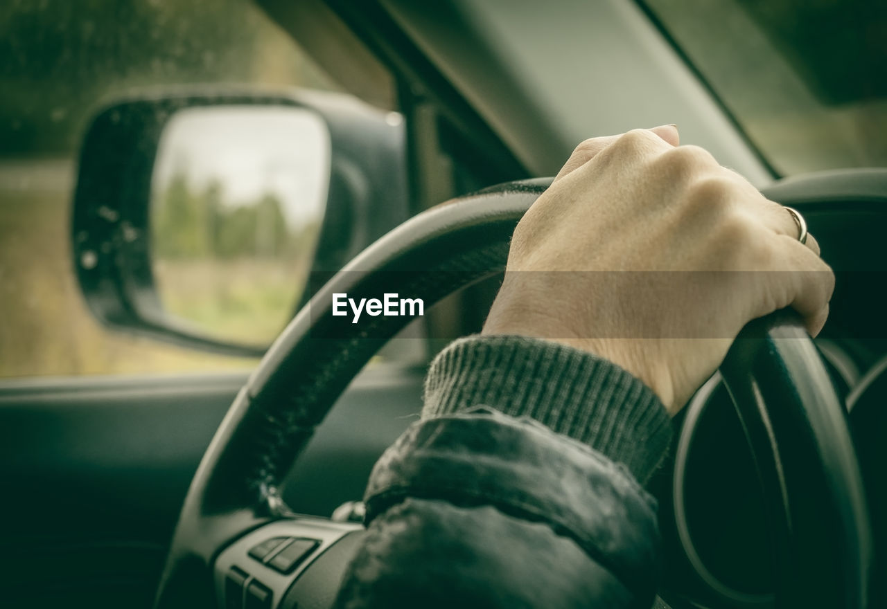 Close-up of hand on steering wheel in car