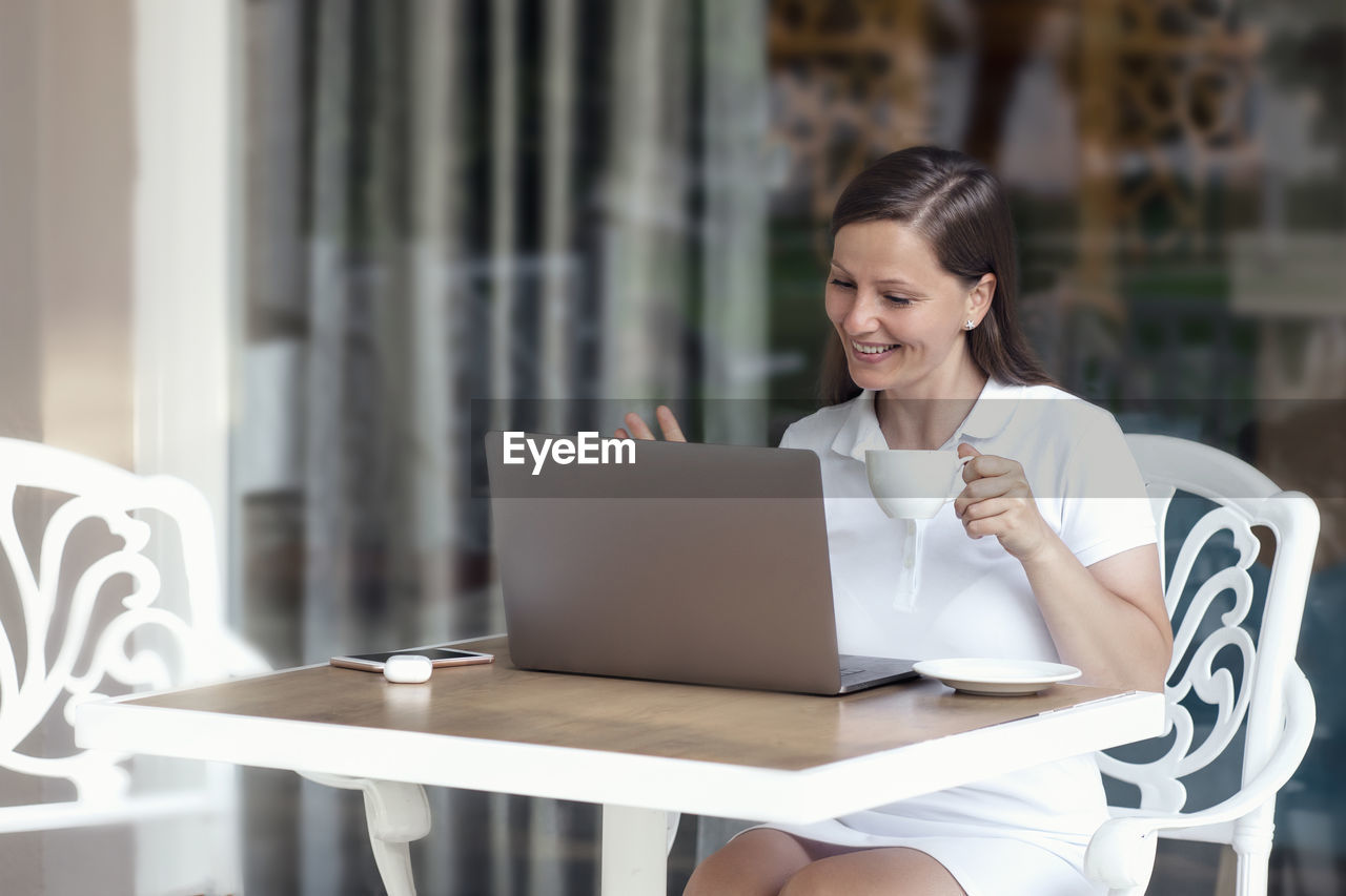 Young woman using phone while sitting on table