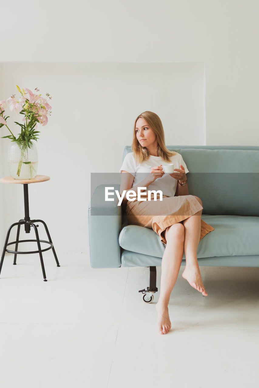 Full length of woman sitting on chair at home