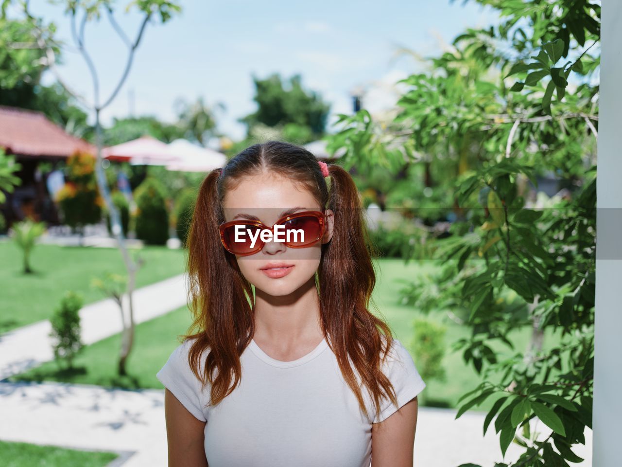 portrait of young woman wearing sunglasses while standing against plants