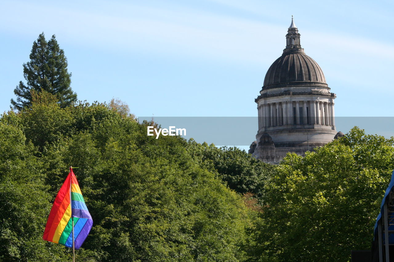 Rainbow flag against trees and state capitol building