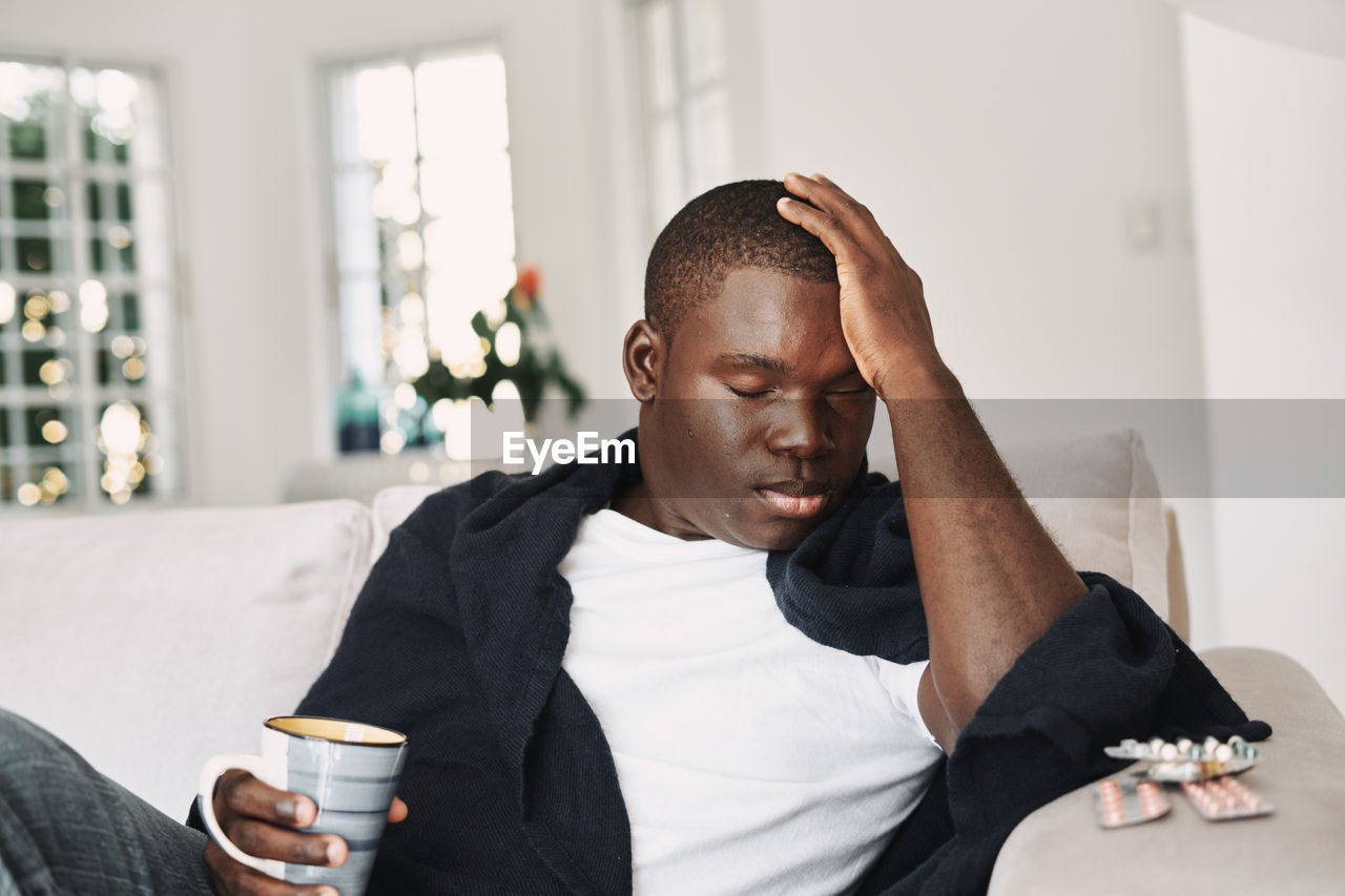 Young man looking away while sitting on table